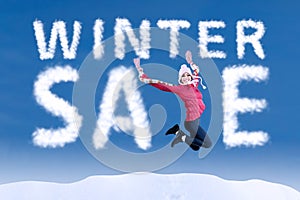 Woman jumping with a winter sale sign