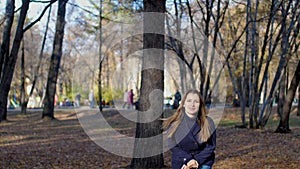 Woman jumps happily among trees and autumn leaves slow motion. 4k 60fps. Girl in a coat walking in the autumn city Park.