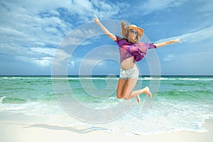 Woman jumps for joy on white sand beach
