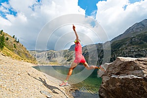 Woman jumps from a rock near a mountain lake