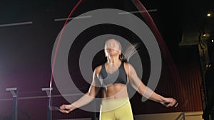 Woman jumps rope actively warming up in large gym hall