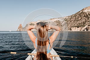 Woman in kayak back view. Happy young woman with long hair floating in kayak on calm sea. Summer holiday vacation and