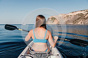 Woman in kayak back view. Happy young woman with long hair floating in kayak on calm sea. Summer holiday vacation and