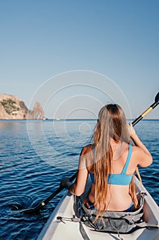 Woman in kayak back view. Happy young woman with long hair floating in kayak on calm sea. Summer holiday vacation and