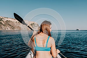 Woman in kayak back view. Happy young woman with long hair floating in kayak on calm sea. Summer holiday vacation and