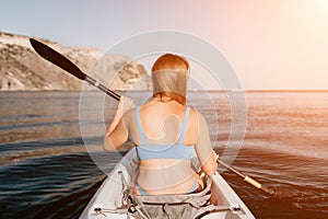 Woman in kayak back view. Happy young woman with long hair floating in kayak on calm sea. Summer holiday vacation and