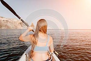 Woman in kayak back view. Happy young woman with long hair floating in kayak on calm sea. Summer holiday vacation and