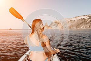 Woman in kayak back view. Happy young woman with long hair floating in kayak on calm sea. Summer holiday vacation and