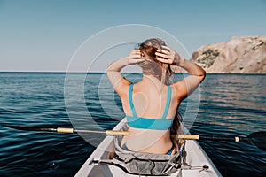 Woman in kayak back view. Happy young woman with long hair floating in kayak on calm sea. Summer holiday vacation and