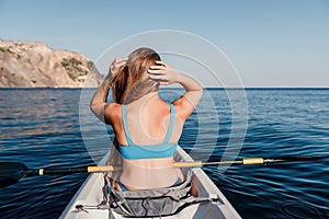 Woman in kayak back view. Happy young woman with long hair floating in kayak on calm sea. Summer holiday vacation and