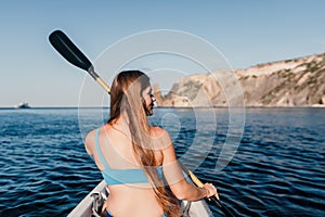 Woman in kayak back view. Happy young woman with long hair floating in kayak on calm sea. Summer holiday vacation and
