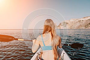 Woman in kayak back view. Happy young woman with long hair floating in kayak on calm sea. Summer holiday vacation and