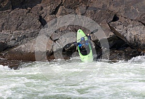 Woman on the kayak launching into the river from the rocks