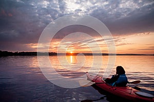 Woman in a kayak on the river on the scenic sunset