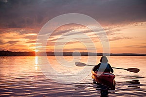 Woman in a kayak on the river on the scenic sunset