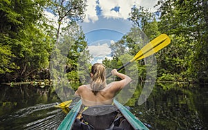 Woman Kayaking down a beautiful tropical jungle river