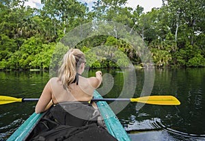 Woman Kayaking down a beautiful tropical jungle river