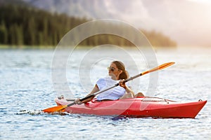 Woman kayaking on river alone with sunset on background