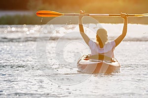 Woman kayaking on river alone with sunset on background