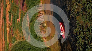 Woman kayaking in river at sunset. Vertical video. Female paddling on kayak