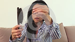 Woman keeping comb with hair in hand.Hair loss concept