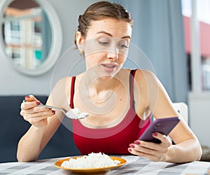 Woman keeping diet, eating rice and texting message