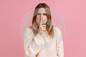 Woman keeping finger on lips making silence gesture, shushing asking to be quiet, secrecy concept.