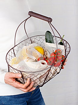 Woman keeps backet with vegetables and fuits in bags