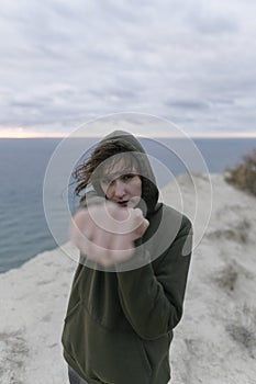 Woman kickboxer training and boxing outdoors. Young confident sportswoman in a sweatshirt beats and makes air strikes