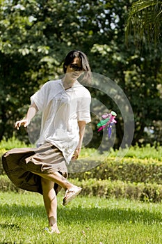 Woman kicking shuttlecock on lawn