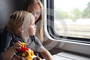 Woman with kid in a train compartment looks out the window. The passenger travels in the train cabin