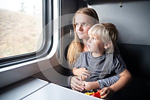 Woman with kid in a train compartment looks out the window. The passengers travels in the train cabin