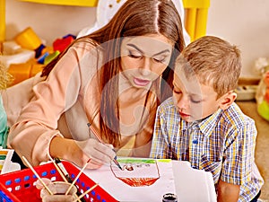 Woman with kids holding colored paper and glue in