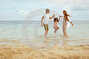 Woman And Kids On Ocean Beach. Young Mother And Son Playing With Little Girl In Sea. Happy Family Enjoying Summer.