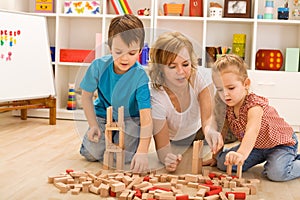 Woman and kids playing with wooden blocks