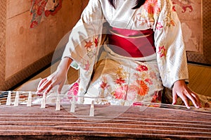 Woman in Kimono dress is playing Koto, Japanese harp