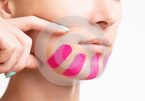 Woman with kinesio tape on chin for facelift. photo