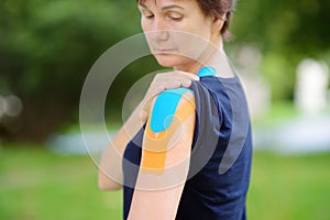 Woman with kinesio tape on her shoulder. Kinesiology, physical therapy, rehabilitation