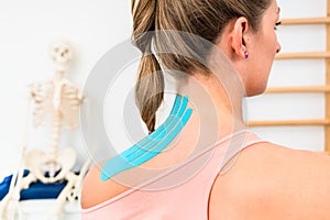 Woman with Kinesio tape on shoulder in physiotherapy