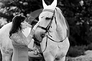 A woman kisses a beautiful white horse. black white photo