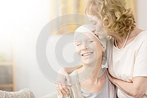 Woman kissing cancer survivor`s temple photo