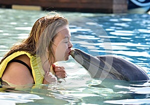 Woman kissing dolphin in pool
