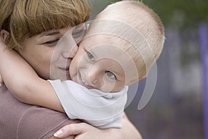 Woman Kissing And Embracing Son In Park