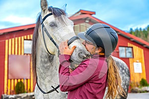 Woman kissing a horse outside an equestrian center