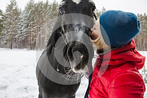 Woman kissing a horse in woods