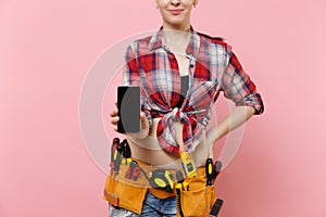 Woman with kit tools belt full of instruments holding showing camera mobile phone with blank black empty screen display