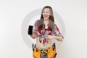 Woman in kit tools belt full of instruments holding showing camera mobile phone with blank black empty screen display