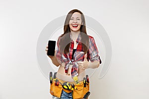 Woman in kit tools belt full of instruments holding showing camera mobile phone with blank black empty screen display