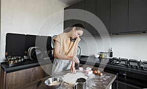 A woman in the kitchen is cooking and talking on the phone. Busy housewife.