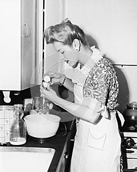 Woman in the kitchen cracking an egg